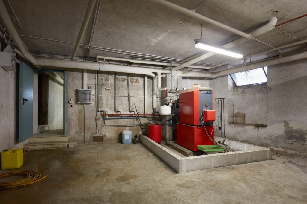 Keller mit rotgefärbter Heizung mit Warmwasserspeicher in älterem Haus